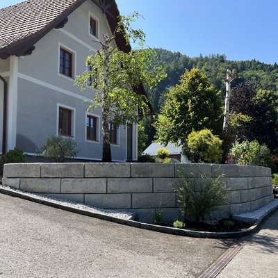 Haus mit bepflanzter Stützmauer aus Betonsteinen in Hanglage
