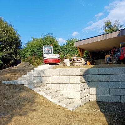 SW-Stützmauer mit Stufenplatten für Hangabfangung und Kellerzugang neben Carport