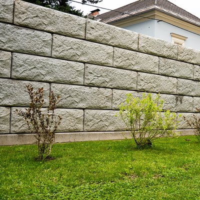 Pflegeleichte Sichtschutzmauer aus Betonsteinen als moderne Alternative zur Thujenhecke im Garten eines Hauses