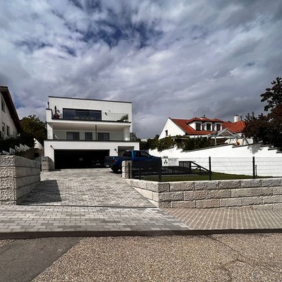 Freistehende Betonmauern rahmen die moderne Einfahrt am Einfamilienhaus stilvoll ein