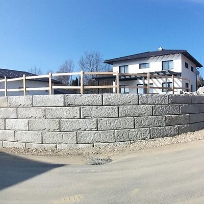 Halbrunde Stützmauer aus Betonsteinen sorgt für Stabilität und klare Grundstücksgrenze am Neubau