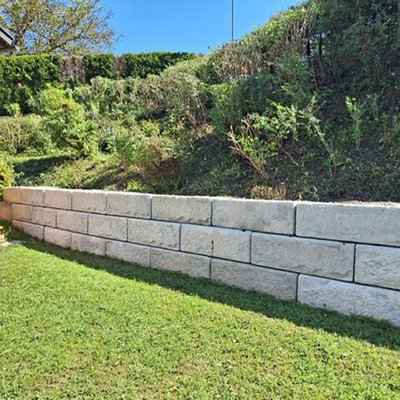 Stützmauer aus hellen Betonblöcken zur Hangbefestigung im Garten – saubere Lösung mit Natursteinoptik entlang der Rasenfläche