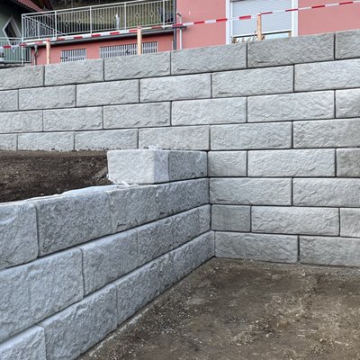 Stützwand mit natürlicher Optik – ideal bei Hanglage und integriertem Parkplatz
