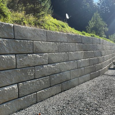 Lange Stützmauer aus Beton zur Stabilisierung einer steilen Böschung am Hang