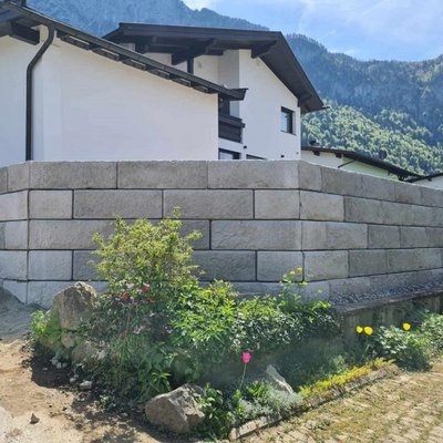 Stützmauer in heller Steinoptik schützt das Grundstück und ergänzt den modernen Garten