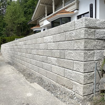 Beton-Stützmauer vor Einfamilienhaus in Hanglage – stabile Lösung direkt an der Grundstücksgrenze