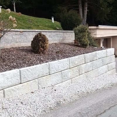 Helle Betonmauer stützt bepflanzte Böschung – ideal für gepflegte Gärten am Hang